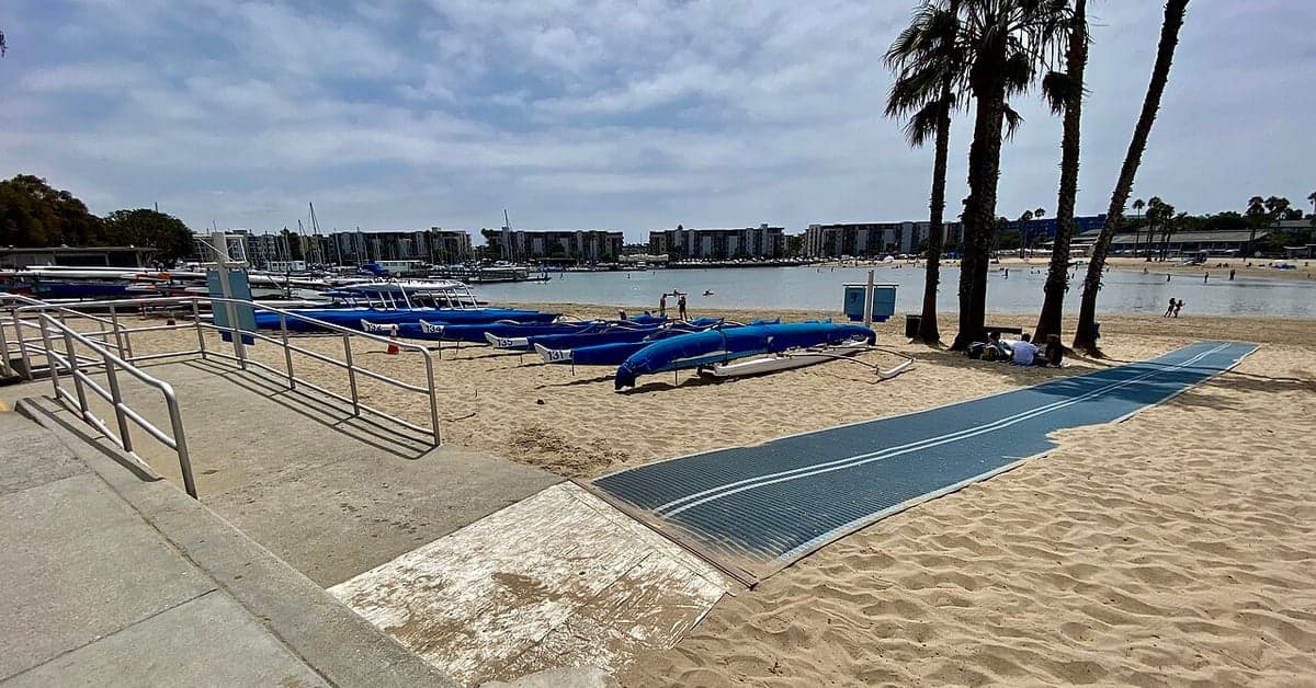 A beach access mat and a beach wheelchair on the sand