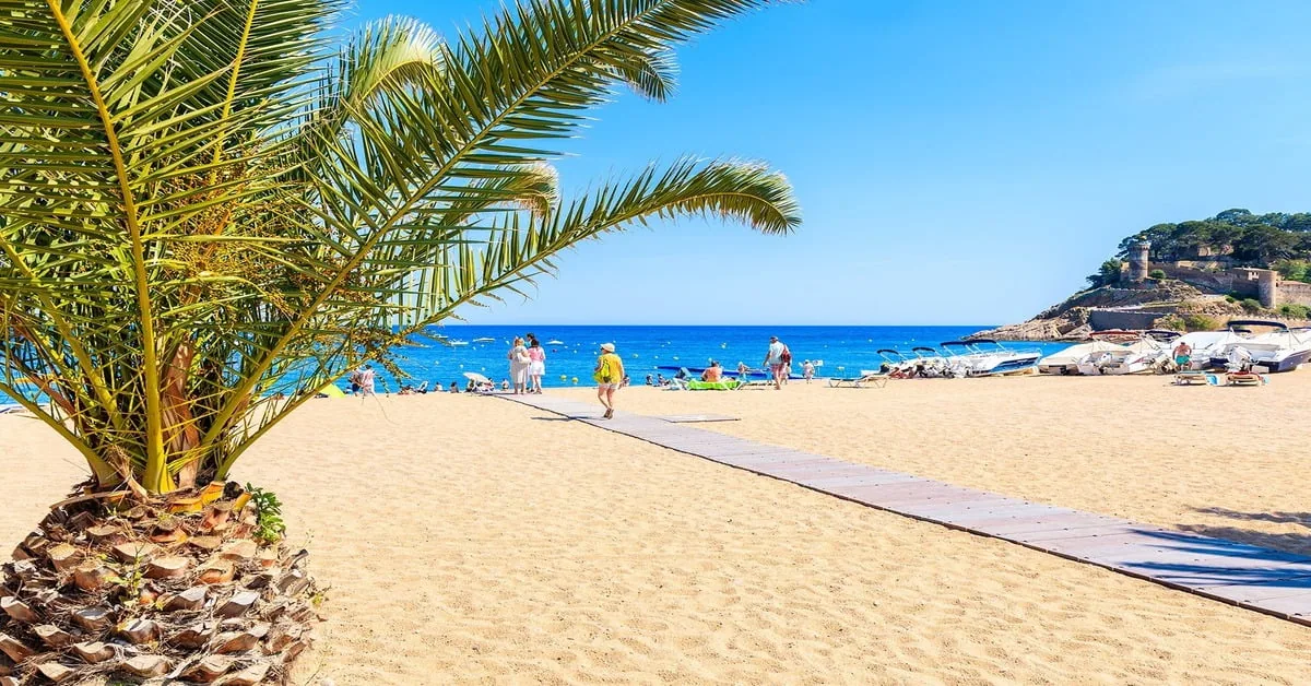 The golden beach of Tossa de Mar with its iconic medieval fortress walls rising above the shore