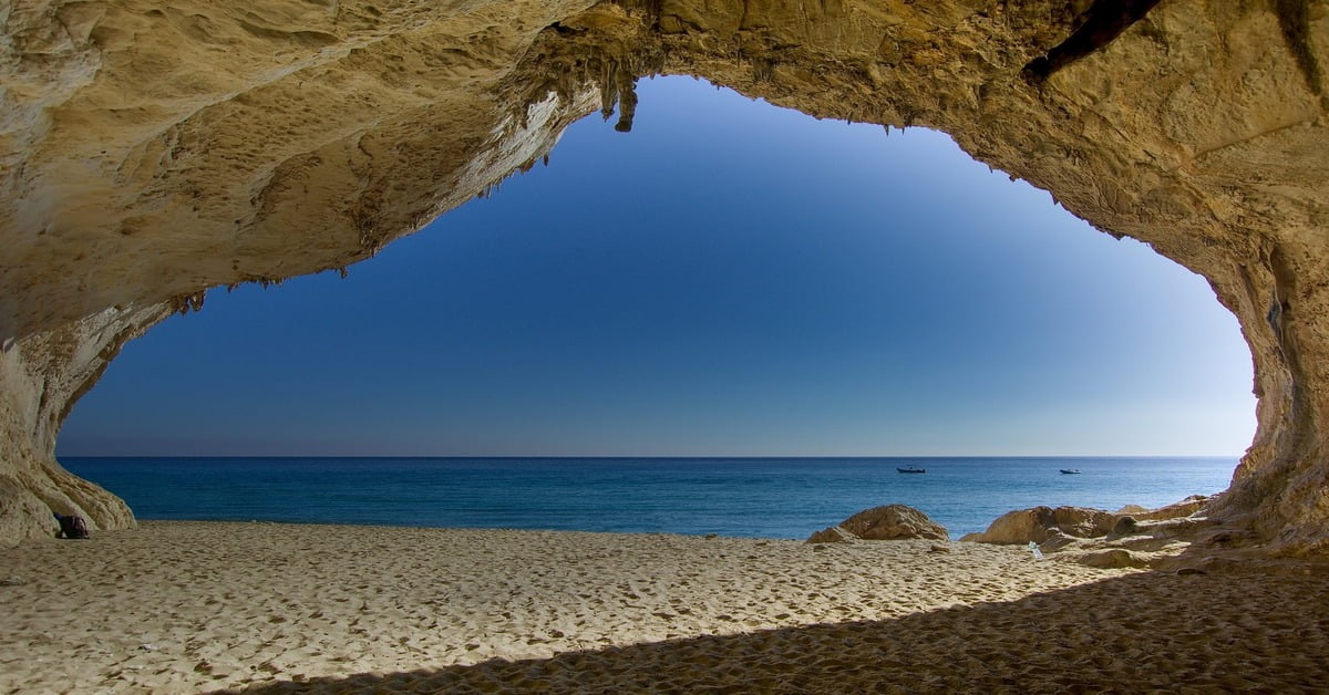 Cala Luna beach in Sardinia with sea caves carved into the surrounding cliffs and soft golden sand