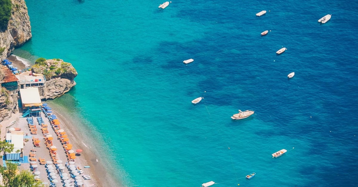 Spiaggia Grande in Positano with colorful cliffside buildings cascading down to the dark sand beach and sparkling sea