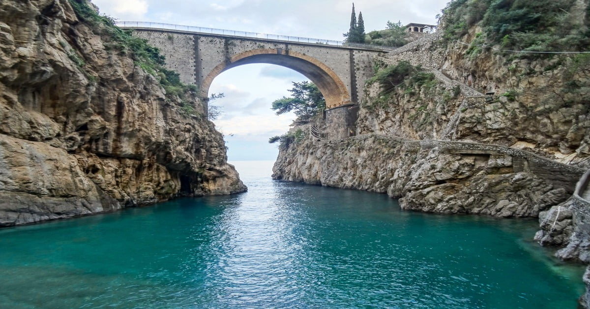 The fjord-like Fiordo di Furore on the Amalfi Coast, a narrow cove with crystal-clear water beneath a stone bridge