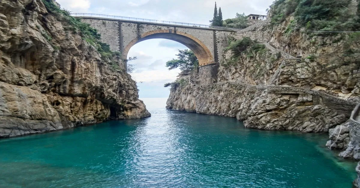 The fjord-like Fiordo di Furore on the Amalfi Coast, a narrow cove with crystal-clear water beneath a stone bridge