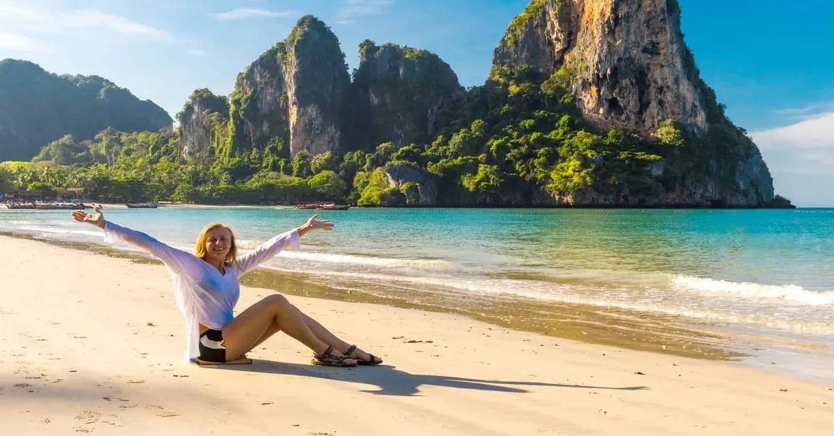 Tropical Phuket beach in Thailand with longtail boats and limestone cliffs