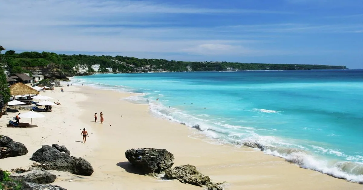 Wide sandy stretch of Kuta Beach in Bali with breaking waves