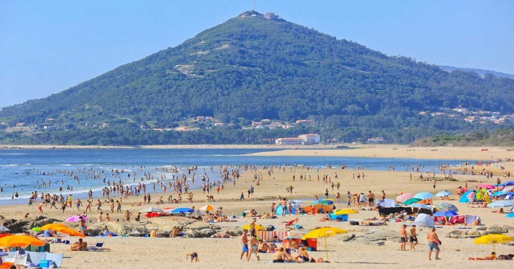 Wide sandy expanse of Praia de Moledo in northern Portugal with mountain views