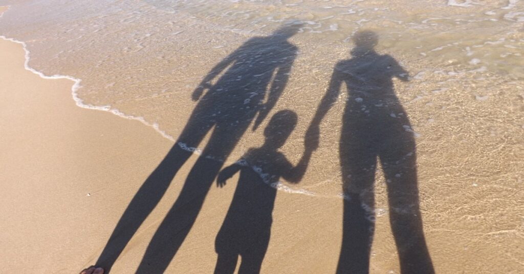 Family enjoying a day at a sandy Italian beach with children playing by the water