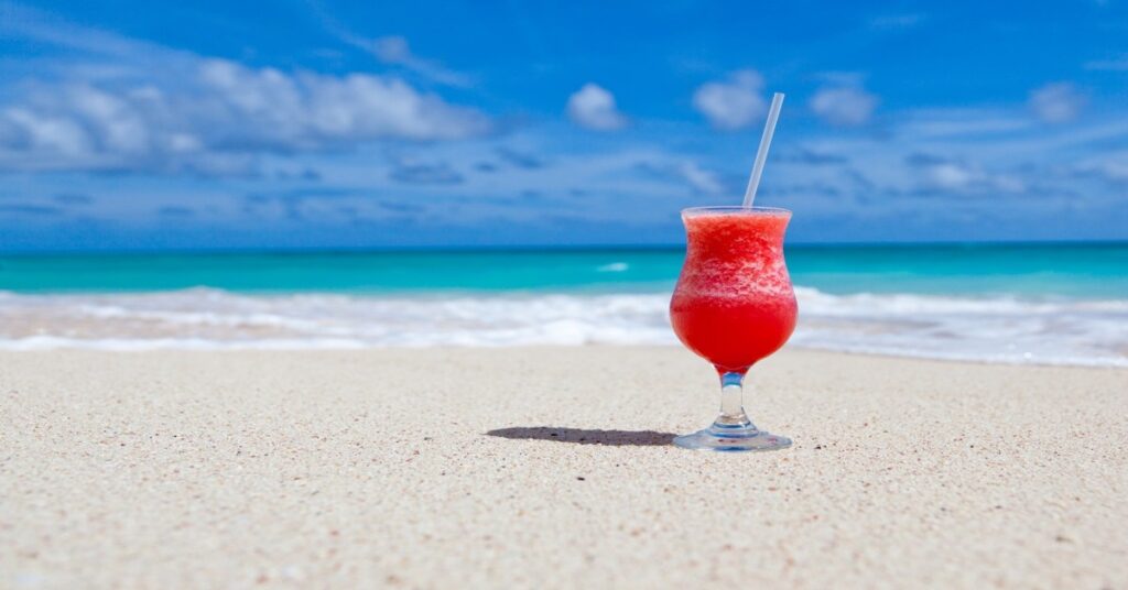 Tropical cocktail on a Caribbean beach with turquoise waters in the background